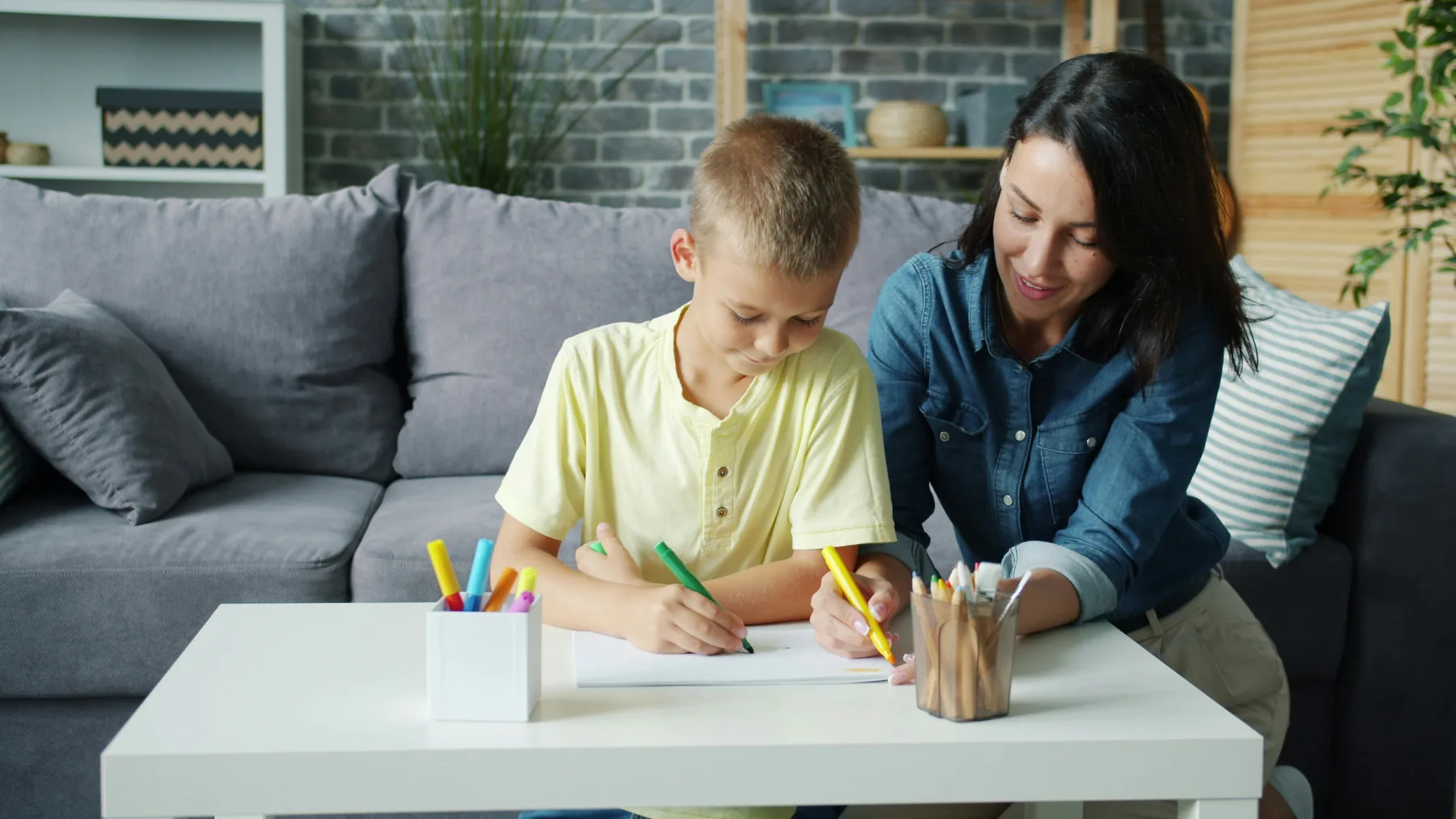 A young person drawing with supportive adult guidance