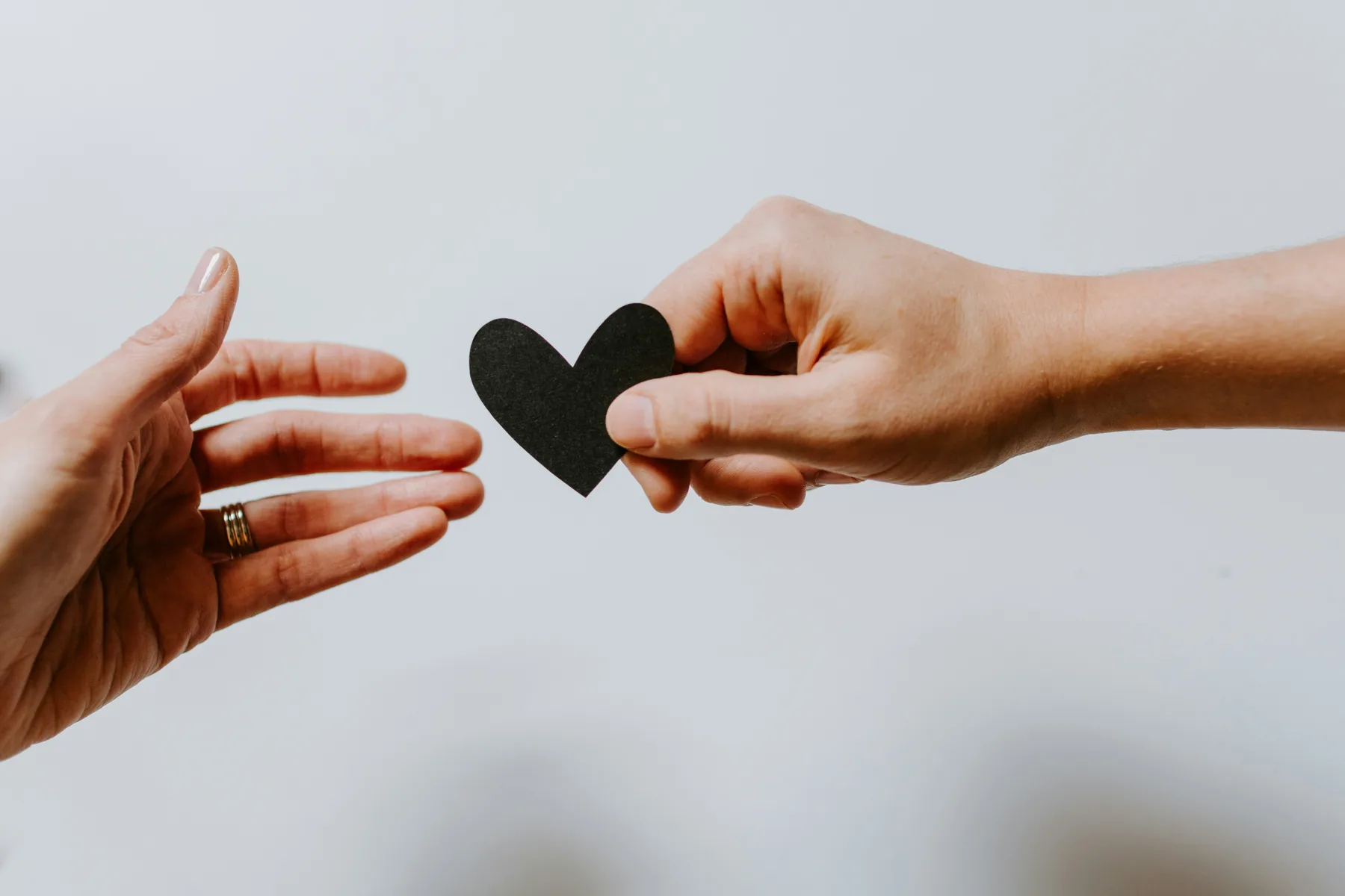 Hands exchanging a small heart symbol, representing support and care